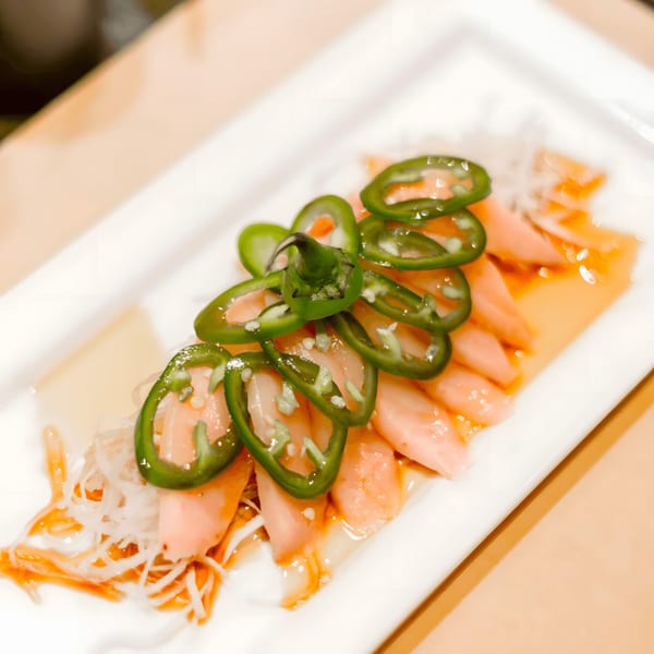 Express Sushi & Teriyaki's salmon sashimi with sliced jalapeños and a light sauce on a white plate.