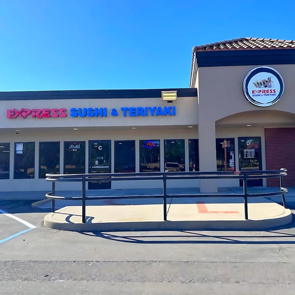 Exterior of Express Sushi & Teriyaki restaurant with a blue sky, showing the storefront and signage.