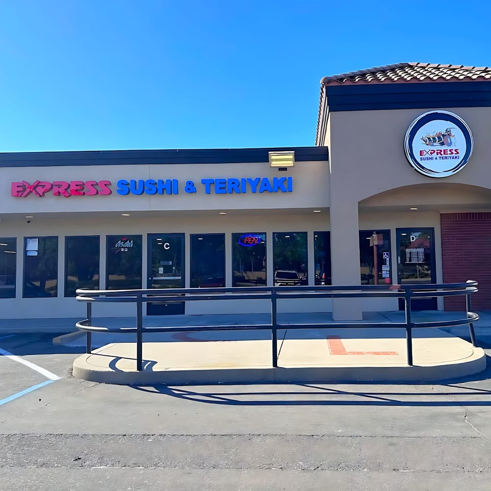 Exterior of Express Sushi & Teriyaki restaurant with a blue sky, showing the storefront and signage.
