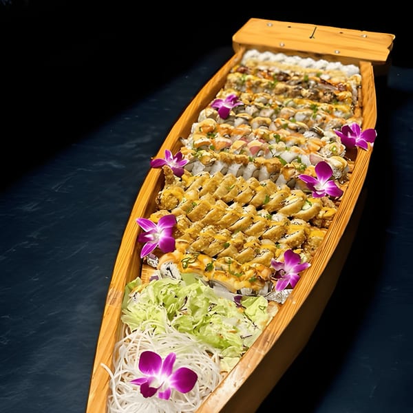 A large wooden boat filled with various sushi rolls, garnished with purple orchids and shredded vegetables.