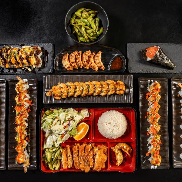 Overhead view of a large Express Sushi & Teriyaki meal spread with various sushi rolls, edamame, and a bento box.
