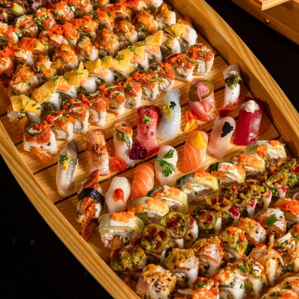 A large wooden boat filled with various sushi rolls, nigiri, and sashimi from Express Sushi & Teriyaki.